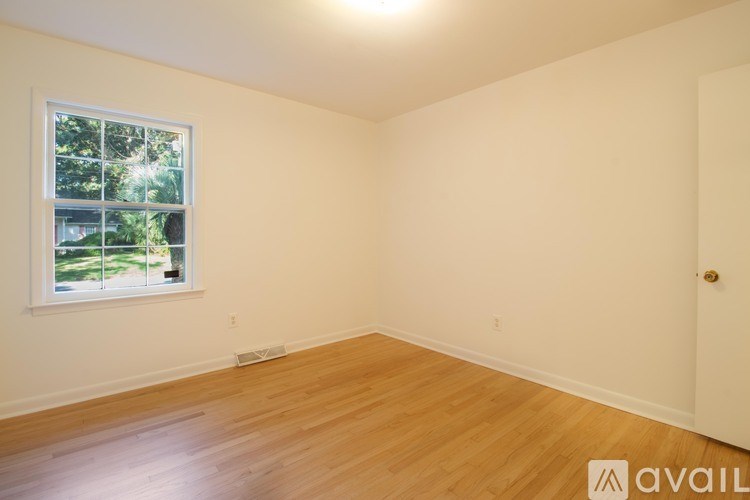 A room with wooden floors and a window showing greenery outside.