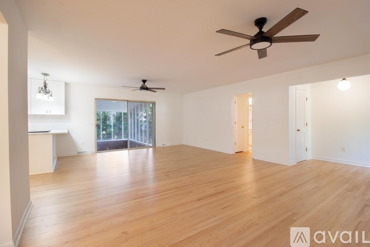 A spacious room with wooden floors and a ceiling fan.