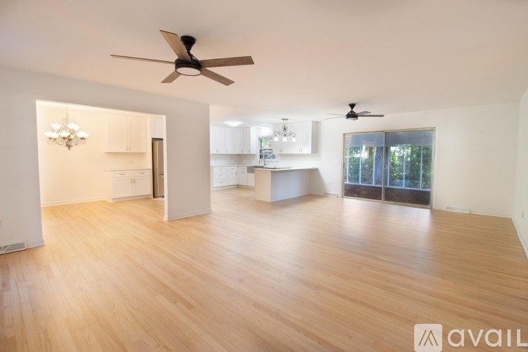 A spacious room with wooden flooring and two ceiling fans.