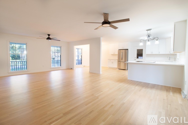 A spacious room with wooden floors and a ceiling fan.