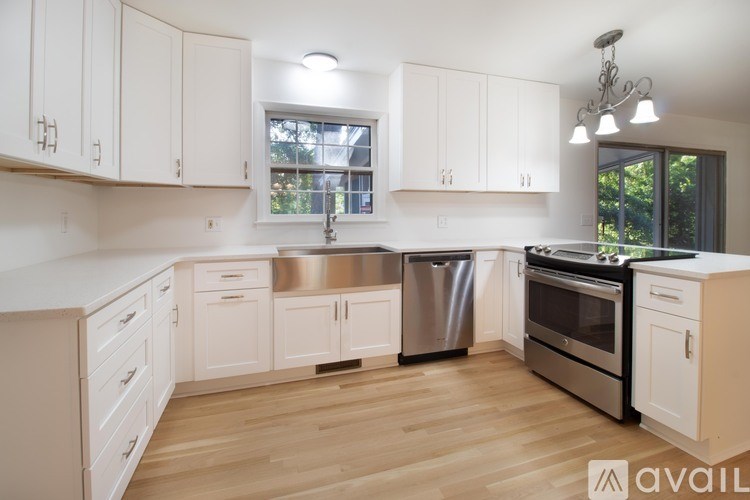 A kitchen with white cabinets and a wooden floor.
