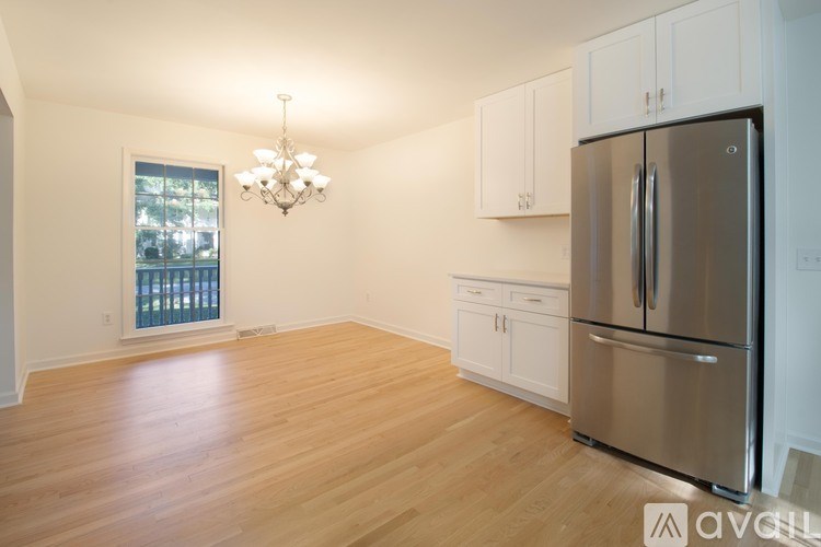 A kitchen with a stainless steel refrigerator and wooden floors.