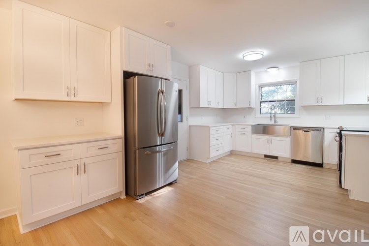 A kitchen with white cabinets and a stainless steel refrigerator.