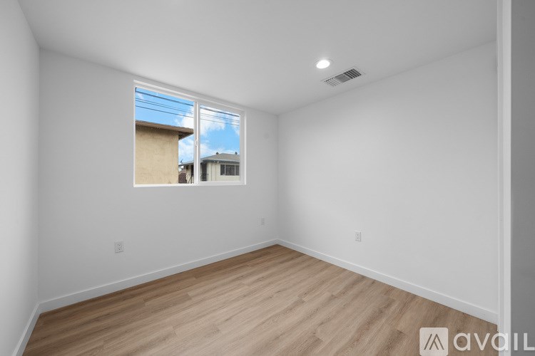 A room with a window showing a view of a house and sky.