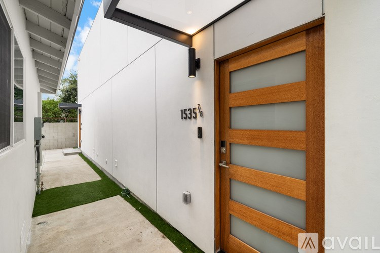 A modern house numbered 1535 with a wooden door and a green lawn.