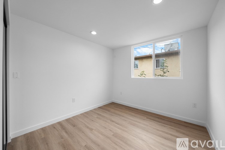 A room with a window showing a view of a building and trees outside.