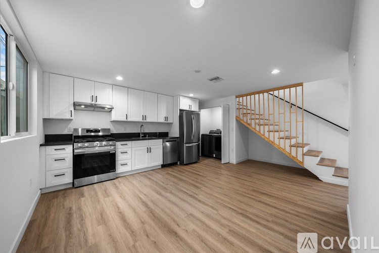 A kitchen with wooden floors and a staircase in the background.