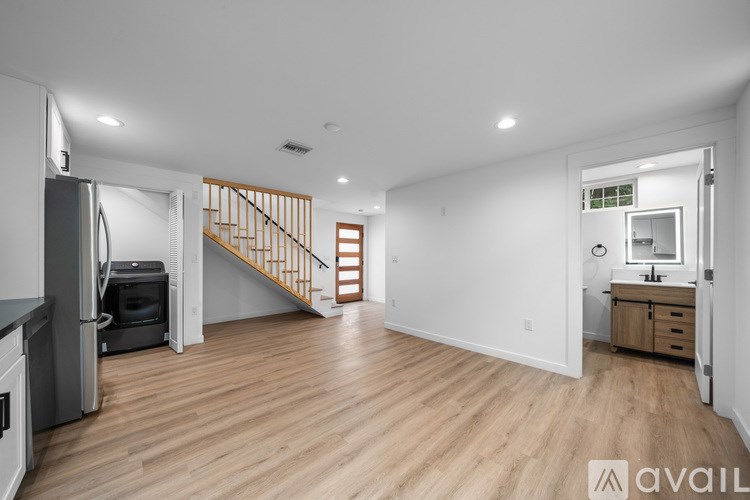 A spacious kitchen with a refrigerator, stove, and wooden floors.