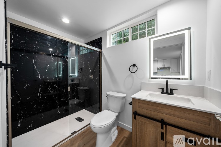A bathroom with a marble shower and a wooden vanity.