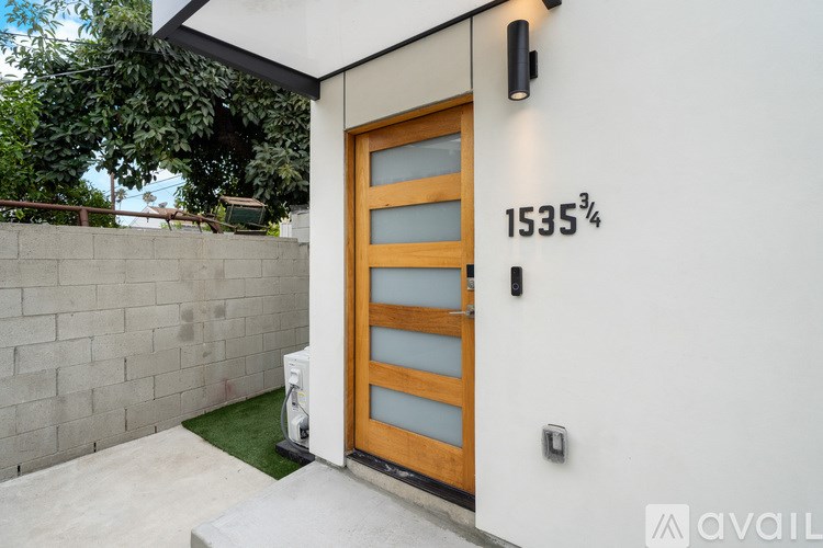 A modern house with a wooden door and a wall with the number 1535 on it.