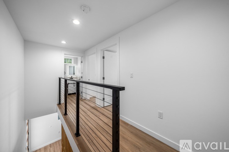 A white room with a wooden floor and a balcony with a black railing.