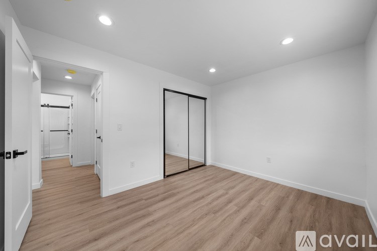 A spacious room with wooden flooring and white walls.