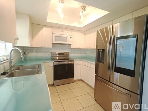 A kitchen with a stainless steel refrigerator and a microwave above the stove.