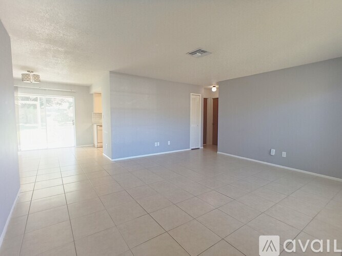 A spacious room with tiled flooring and a door on the right.