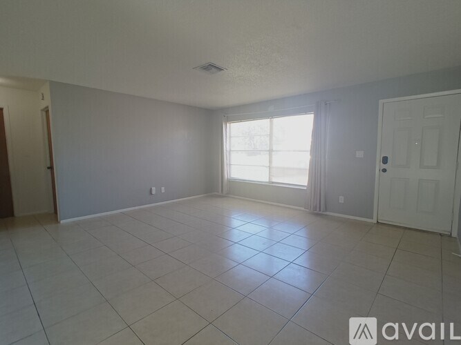 A spacious room with a tiled floor and a large window with curtains.