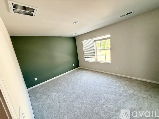 A room with a window and a carpeted floor.