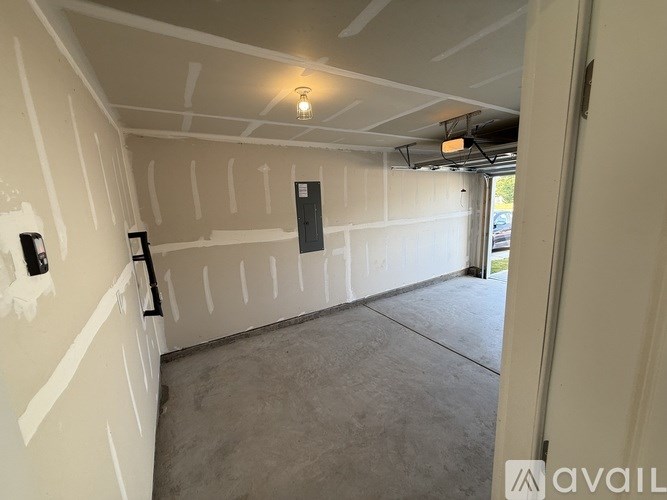A room with drywall installed up to the ceiling and a doorway leading to another room.
