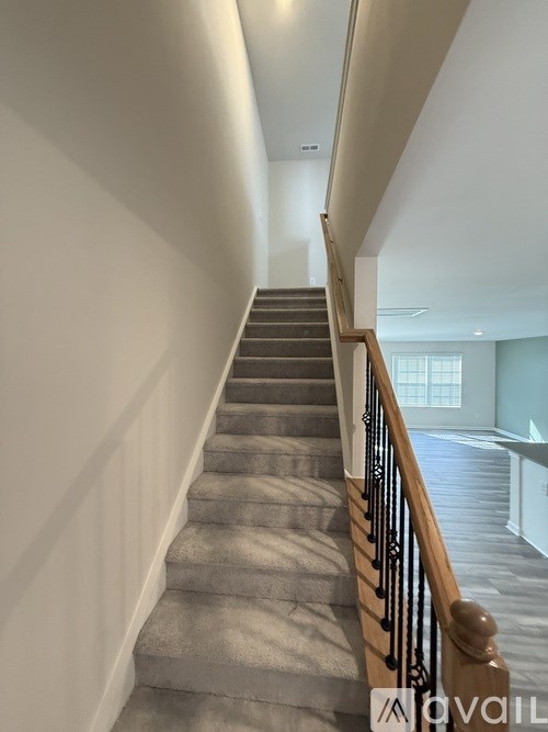 A staircase with a wooden handrail and a carpeted runner.