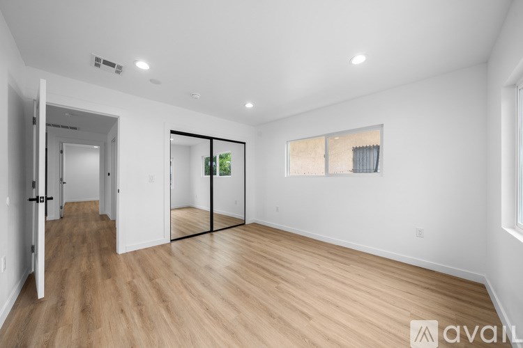 A spacious room with wooden flooring and white walls.