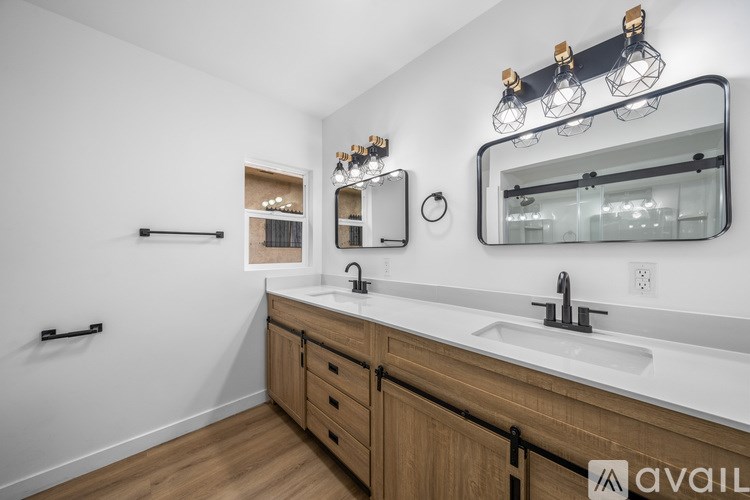 A bathroom with a white sink and a mirror with lights above it.