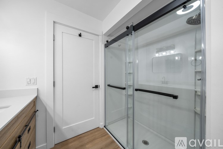 A bathroom with a glass shower door and a white door.