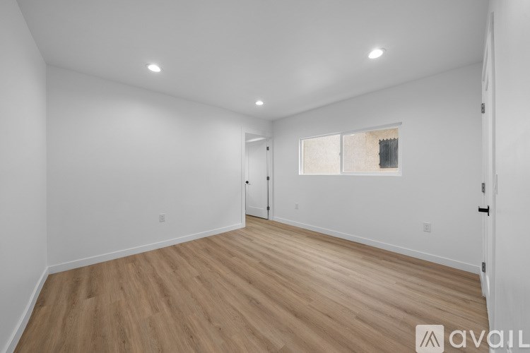 A spacious room with wooden flooring and white walls.