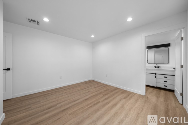A spacious room with wooden flooring and white walls.