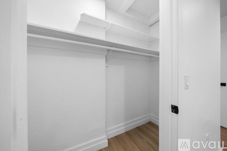 A white room with a door and a wooden floor.