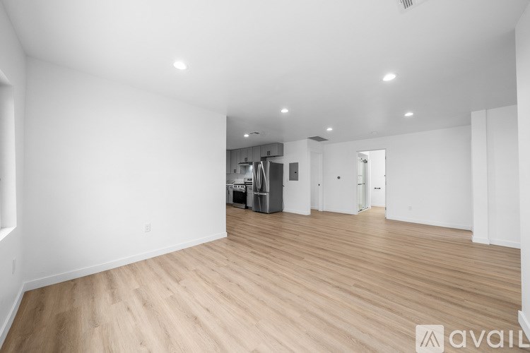 A spacious room with wooden flooring and white walls.