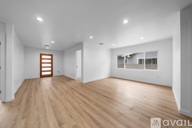 A spacious room with wooden flooring and white walls.