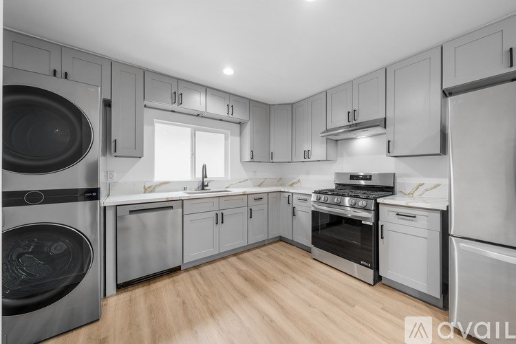 A modern kitchen with stainless steel appliances and wooden flooring.