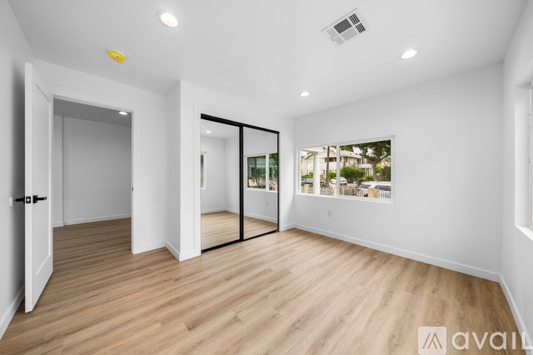 A spacious room with wooden flooring and white walls.