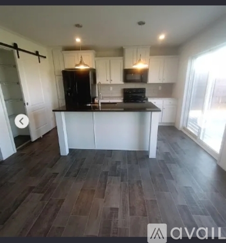 A kitchen with white cabinets and a black fridge.