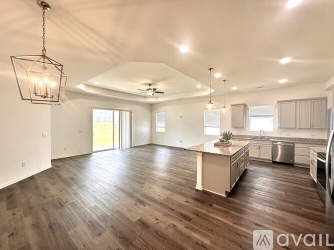 A spacious kitchen and living room with wooden floors and white walls.
