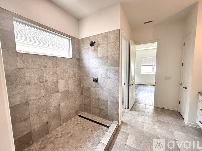 A tiled bathroom with a walk-in shower and a window.