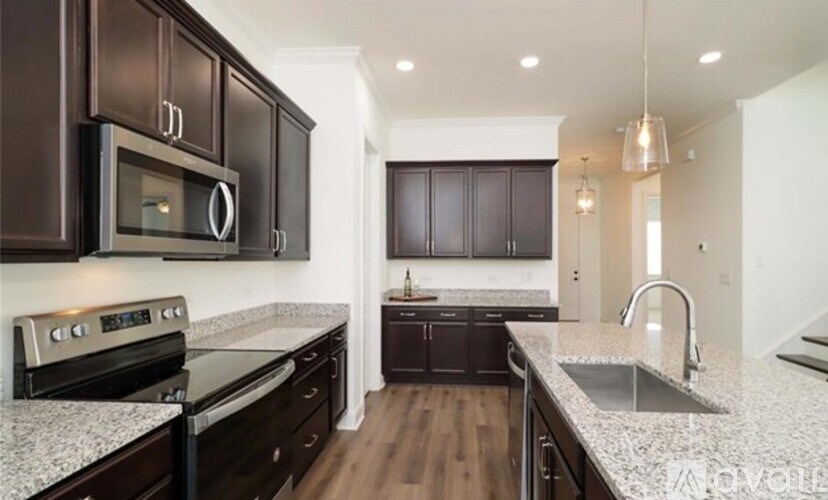 A modern kitchen with dark brown cabinets and a granite countertop.