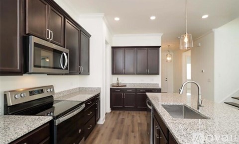 A modern kitchen with dark brown cabinets and a granite countertop.