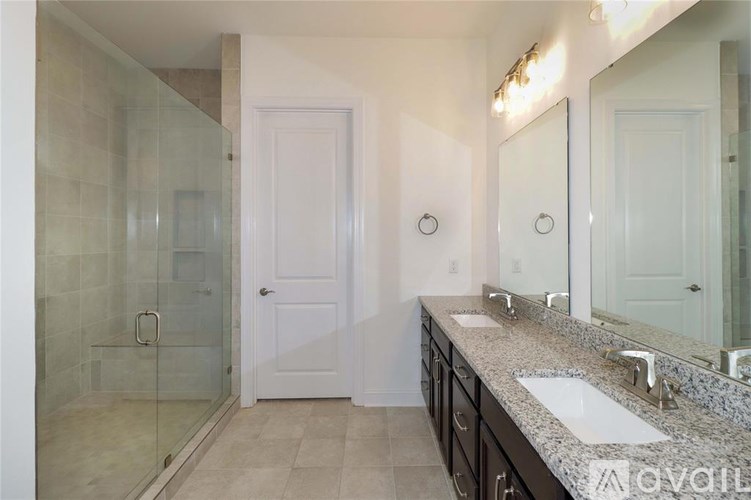 A bathroom with a glass shower door and a white door.