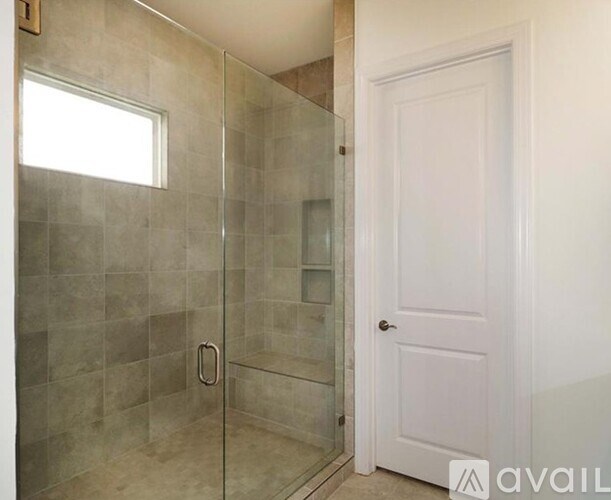 A bathroom with a glass shower stall and a white door.