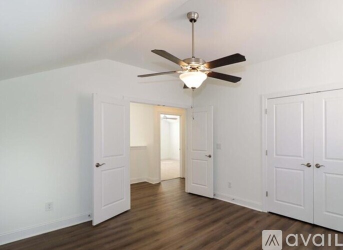 A room with a ceiling fan and wooden floors.