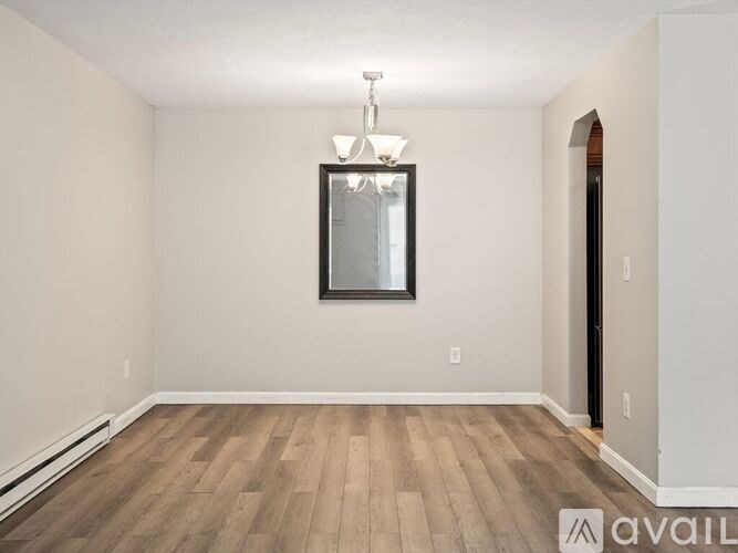 A room with wooden flooring and a chandelier hanging from the ceiling.