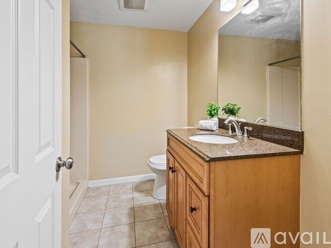 A bathroom with a toilet, sink, and mirror.