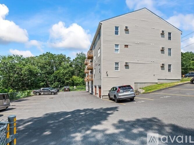 A parking lot with a building and cars parked in front.