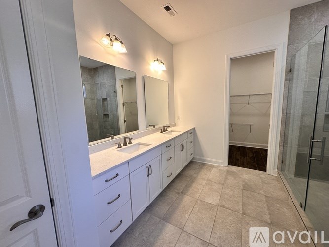A bathroom with a white vanity and a walk-in shower.