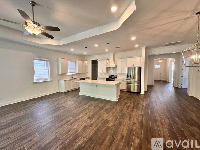 A spacious kitchen with wooden floors and a ceiling fan.