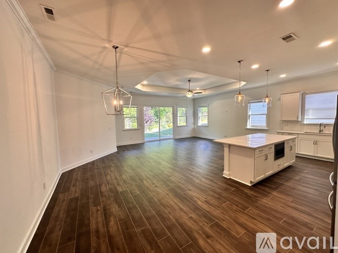 A spacious kitchen and living room with wood flooring and white walls.