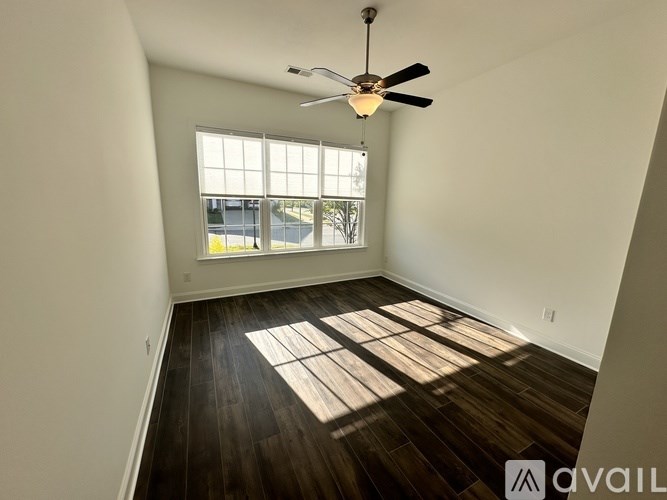 A room with a ceiling fan and wooden flooring.