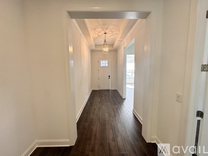 A long hallway with wood floors and white walls.
