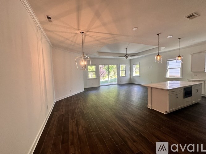 A spacious kitchen and living room with wooden floors and pendant lights.