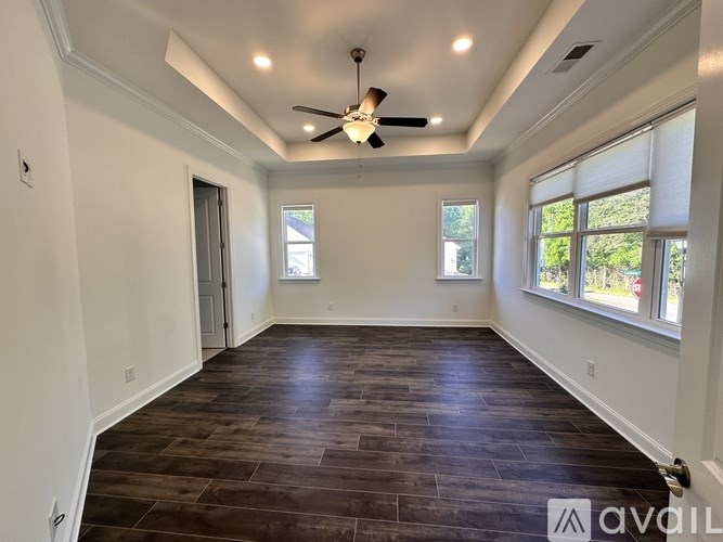 A spacious room with a ceiling fan and wooden flooring.